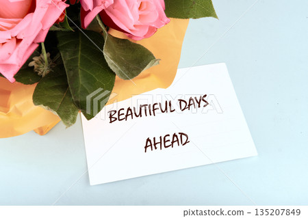 A soft bouquet of pink Roses rests beside a card promising Beautiful Days Ahead, hinting at hope and brighter moments yet to come on a radiant day A soft bouquet of pink Roses rests beside a card promising Beautiful Days Ahead, hinting at hope and brighter moments yet to come on a radiant day 135207849