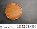 Round wooden chopping board with visible grain and rustic appearance, Circular wooden cutting platform with natural grain and warm tones for culinary presentation 135208464
