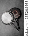 Vintage kitchen scenes, Rustic cookware with signs of frequent use, Weathered pots and pans with stains and patina evoke nostalgic kitchen memories and timeless stories 135208468