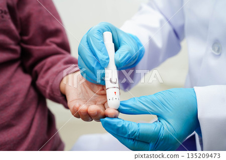 Asian senior woman using lancet pen on senior patient finger for check sample blood sugar level to treatment diabetes. Asian senior woman using lancet pen on senior patient finger for check sample blood sugar level to treatment diabetes. 135209473