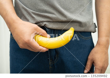 Male stands holding a banana, penis health. Male stands holding a banana, penis health. 135209492