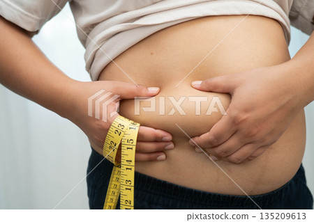 Asian woman use hand to squeeze fat belly big size overweight and obesity. Asian woman use hand to squeeze fat belly big size overweight and obesity. 135209613