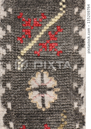 Dark grey woven fabric texture with red and white geometric embroidery 135209764