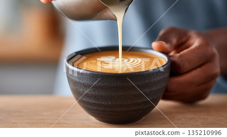 Barista pouring milk into coffee cup with latte art 135210996