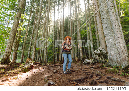 Woman with backpack hiking outdoors in the Forest. Trekking in the Pine Woods. Hiking lifestyle Woman with backpack hiking outdoors in the Forest. Trekking in the Pine Woods. Hiking lifestyle 135211195
