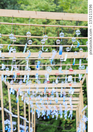 藍色玻璃風鈴懸掛在木框上，映襯著綠色的夏日景色。 135211396