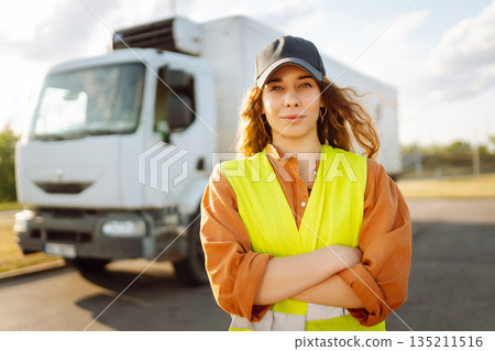 Portrait of woman truck driver in casual clothes standing in front of truck. Transport industry Portrait of woman truck driver in casual clothes standing in front of truck. Transport industry 135211516