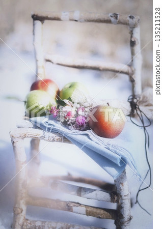 Apples on a birch chair in the snow 135211528