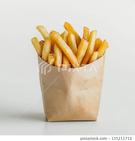 A brown paper bag filled with golden, crispy French fries is shown against a white background. 135211718