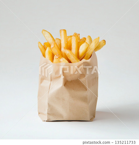 A brown paper bag filled with golden, crispy French fries is shown against a white background. 135211733