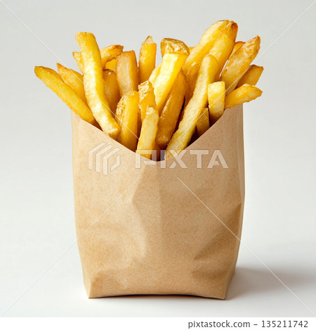 A brown paper bag filled with golden, crispy French fries is shown against a white background. A brown paper bag filled with golden, crispy French fries is shown against a white background. 135211742
