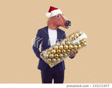 Portrait of man wearing funny horse costume holding big set of Christmas tree balls Portrait of man wearing funny horse costume holding big set of Christmas tree balls 135211977
