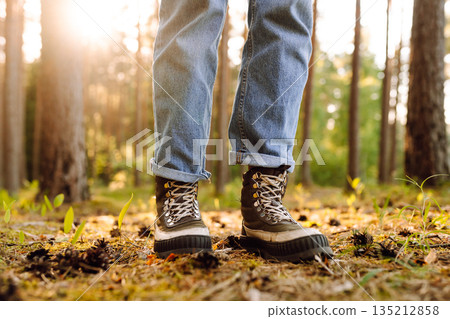 Hiker's boots stepping on a blanket of fallen autumnal orange leaves in the forest. Travel Hiker's boots stepping on a blanket of fallen autumnal orange leaves in the forest. Travel 135212858