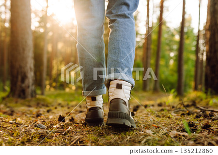 Hiker's boots stepping on a blanket of fallen autumnal orange leaves in the forest. Travel Hiker's boots stepping on a blanket of fallen autumnal orange leaves in the forest. Travel 135212860