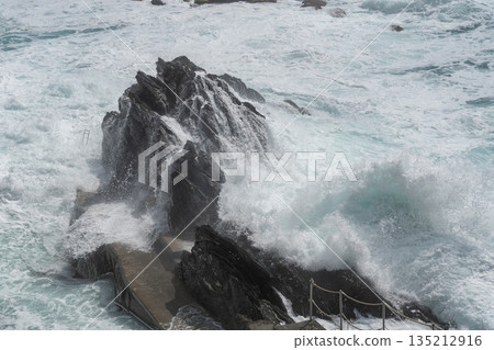 Strong sea waves crashing against dark coastal rocks. Dramatic motion, natural power and wild seascape atmosphere, ideal for nature and ocean strength concepts Strong sea waves crashing against dark coastal rocks. Dramatic motion, natural power and wild seascape atmosphere, ideal for nature and ocean strength concepts 135212916