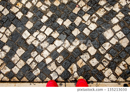 Red Shoes on Vintage Black and White Stone Mosaic Pavement, Top View 135213030