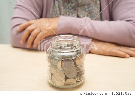 Retired Asian elderly woman counting coins money and worry about monthly expenses and treatment fee payment. Retired Asian elderly woman counting coins money and worry about monthly expenses and treatment fee payment. 135213052