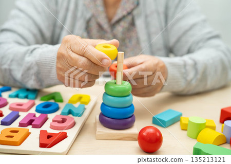 Asian elderly woman playing enhancing skill board game. 135213121