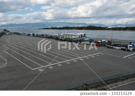 A vast trailer waiting area and Expo wharf on Yumeshima Island overlooking Osaka Bay and the Rokko Mountains (logistics, harbor, scenery) A vast trailer waiting area and Expo wharf on Yumeshima Island overlooking Osaka Bay and the Rokko Mountains (logistics, harbor, scenery) 135213129