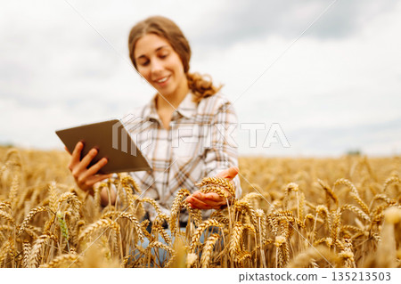 Woman farmer with digital tablet in agricultural field. Smart farm Woman farmer with digital tablet in agricultural field. Smart farm 135213503