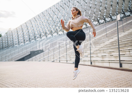 Young woman in sportswear is training outdoors. Sports concept, healthy body. Young woman in sportswear is training outdoors. Sports concept, healthy body. 135213628