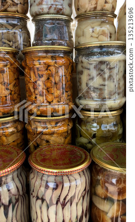 Different types of canned mushrooms in jars on the shelf. 135213696