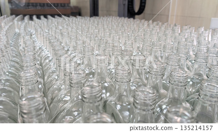 Empty glass bottles arranged on a production line in a large factory Empty glass bottles arranged on a production line in a large factory 135214157
