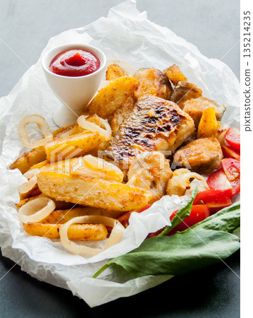 Portion of fish and chips with ketchup sauce, baked potatoes with seafood with vegetables. 135214235