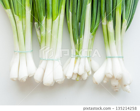 Fresh green leek onion on wooden background, top view bunch of greens on the table. Fresh green leek onion on wooden background, top view bunch of greens on the table. 135214258