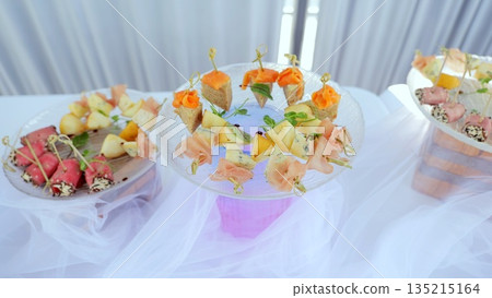 Gourmet appetizers arranged on sleek glass plates, featuring skewered delicacies showcasing sophisticated catering design for upscale event styling Gourmet appetizers arranged on sleek glass plates, featuring skewered delicacies showcasing sophisticated catering design for upscale event styling 135215164