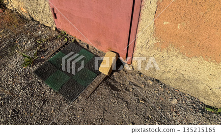 Improvised security: a yellow brick used to hold a metal door shut instead of a lock. Improvised security: a yellow brick used to hold a metal door shut instead of a lock. 135215165