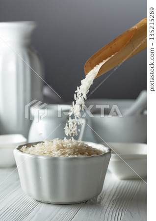 Raw organic rice is poured in white bowl. Raw organic rice is poured in white bowl. 135215269