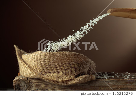 Rice is poured into a burlap bag. 135215276