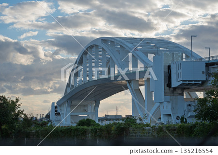 The huge arch of Yumemai Bridge and its floating pontoon structure (floating swing bridge) seen from the Maishima side of Osaka The huge arch of Yumemai Bridge and its floating pontoon structure (floating swing bridge) seen from the Maishima side of Osaka 135216554