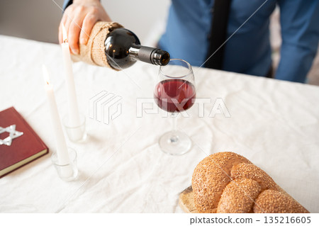 Pouring red kosher wine into glass. Shabbat Shalom concept. Pouring red kosher wine into glass. Shabbat Shalom concept. 135216605