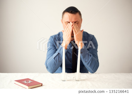 Jewish man praying with Shabbat candles. Shabbat Shalom. 135216641
