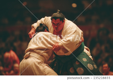 Sumo wrestler engages in a fierce competition throwing opponent over shoulder during match 135216655