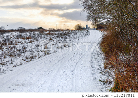 Snow covered rural road under winter sky 135217011