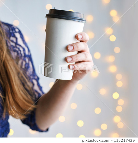 Caucasian female holding coffee cup against soft bokeh light background Caucasian female holding coffee cup against soft bokeh light background 135217429
