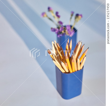 Arrangement of yellow pencils in blue holder with purple flowers in soft light Arrangement of yellow pencils in blue holder with purple flowers in soft light 135217450