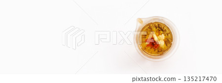 Glass teapot with blooming flower tea on white background with minimalist 135217470
