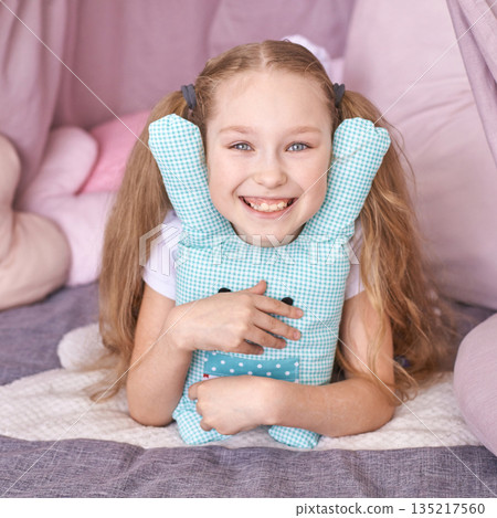Smiling caucasian young girl hugging blue checkered teddy bear indoor playful 135217560