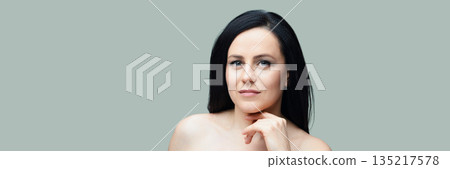 Confident young caucasian female with long black hair against a grey background 135217578