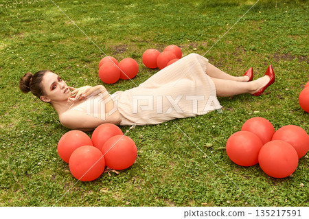 Young caucasian female in white dress relaxing on grass surrounded by red Young caucasian female in white dress relaxing on grass surrounded by red 135217591