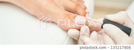 Close-up of toenail painting in spa pedicure session with light pink polish Close-up of toenail painting in spa pedicure session with light pink polish 135217808