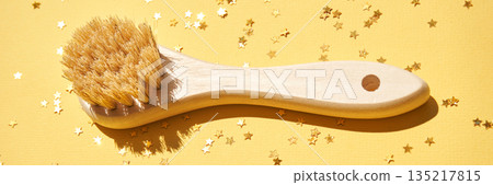 Wooden body brush with natural bristles on yellow background with gold star 135217815