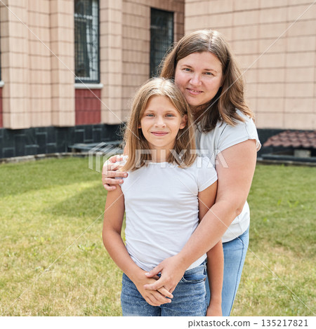 Caucasian adult female and young female smiling outdoors in casual attire 135217821
