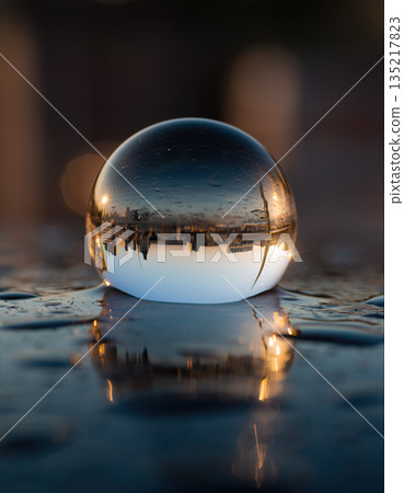Reflection of city skyline in a crystal ball on a wet surface at sunset 135217823