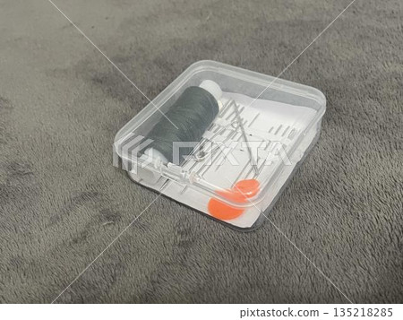 A tailor's sewing kit on a table. Needles, thread, and fabric for sewing. A tailor's sewing kit on a table. Needles, thread, and fabric for sewing. 135218285