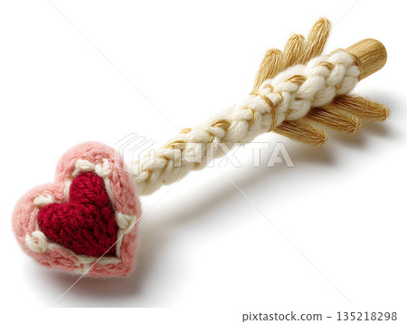Knitted Cupid's arrow with pink heart and gold accents on white background Knitted Cupid's arrow with pink heart and gold accents on white background 135218298